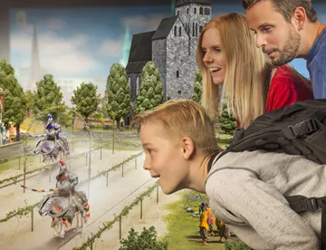 Eine Familie schaut sich ein Ritterturnier in Miniatur im Little BIG City Berlin an 
