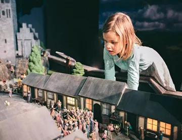 Kleines Mädchen betrachtet eine historische Miniatur des mittelalterlichen Berlins im Little BIG City Berlin